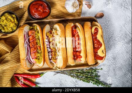 Hot dog completamente carico con condimenti assortiti su un vassoio deliziosi hot-dog con salumi di maiale e manzo. Sfondo bianco. Vista dall'alto Foto Stock