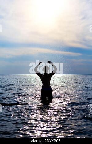 Happy Man Silhouette con spruzzi in acqua sul Tramonto sfondo Foto Stock