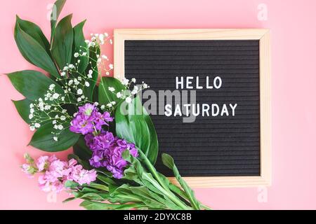Ciao Sabato testo su bordo nero lettera e bouquet fiori colorati su sfondo rosa. Concetto Happy Sabato. Modello per cartolina, biglietto d'auguri Foto Stock