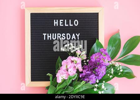 Ciao Giovedi testo su bordo nero lettera e bouquet fiori colorati su sfondo rosa. Concetto Happy Giovedi. Modello per cartolina, biglietto d'auguri Foto Stock