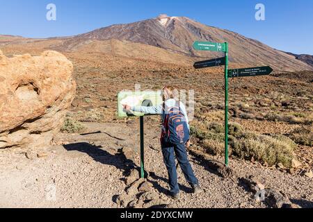 Donna camminatore ai cartelli e le indicazioni sui sentieri per il Pico Viejo nel Parco Nazionale di Las Canadas del Teide, Tenerife, Isole Canarie, Spagna Foto Stock