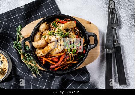 Udon mescolare gli spaghetti con il pollo e le verdure in padella. Sfondo grigio. Vista dall'alto Foto Stock