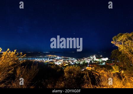 Cielo stellato sul castello, città e porto di Castiglione della Pescaia sulla vasta baia della Maremma, Toscana, Italia Foto Stock