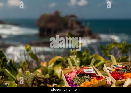 Immagine ravvicinata di Canang Sari (offerte giornaliere) E Tanah Lot Tempio in sfondo sfocato Foto Stock