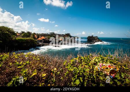 Offerte giornaliere indù canang sari sul cespuglio che si affaccia su Tanah Tempio Lot vicino al mare Foto Stock