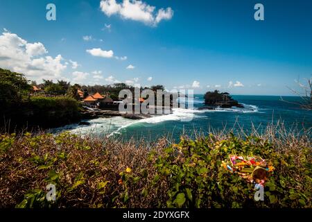 Offerte di puja indù sul tempio Tanah Lot sfondo vicino il mare ondulato Foto Stock