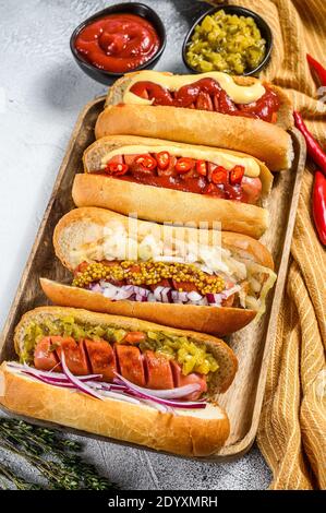 Hot dog completamente carico con condimenti assortiti su un vassoio deliziosi hot-dog con salumi di maiale e manzo. Sfondo bianco. Vista dall'alto Foto Stock