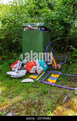 Sacchetti di plastica e altri rifiuti in un bidone straripante in natura Foto Stock