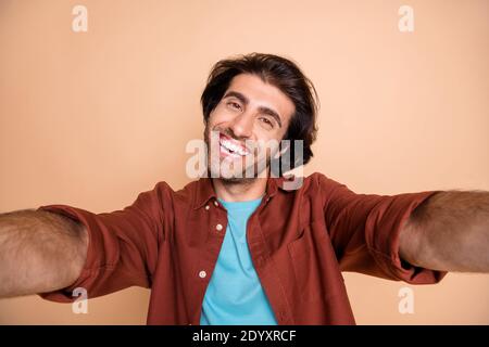 Ritratto fotografico di un uomo sorridente che prende selfie isolato su pastello sfondo di colore beige Foto Stock