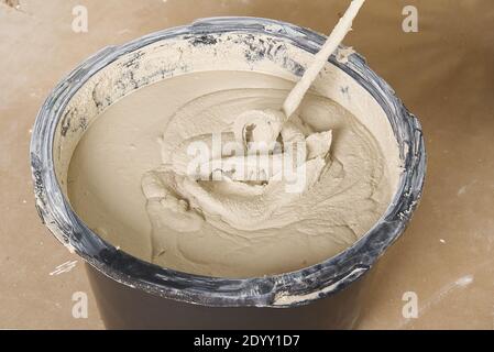 il maestro mescola il gesso in un secchio. Ristrutturazione casa piatta, master mescolato il mortaio in un secchio di plastica con miscelatore Foto Stock
