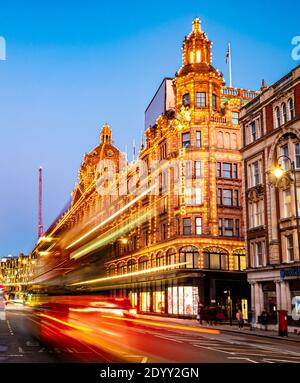 Londra, Inghilterra, Regno Unito - 27 dicembre 2020: Tracce rosse di autobus a due piani di fronte al famoso grande magazzino di lusso Harrods a Londra di notte Foto Stock