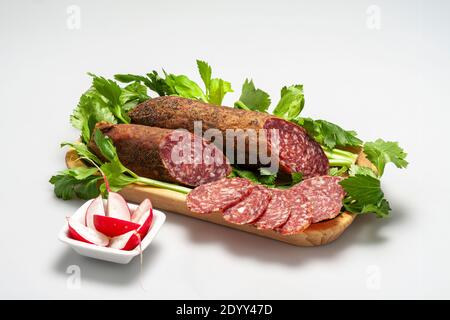 Tagliere con fette di salame artigianale e ravanelli Foto Stock