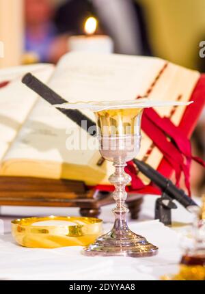 altare con ostia che diventa corpo di gesù cristo e calice per il vino, sangue di cristo, con il libro per la messa dei fedeli Foto Stock