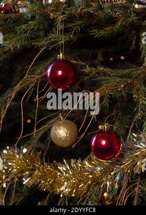 Immagine verticale di un albero di Natale non annaffiato con aghi di pino caduto che si spargono dai rami con decorazioni. E Tinsel , copia spazio in backgro Foto Stock