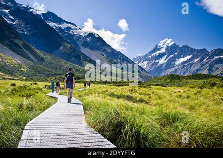 I camminatori camminano lungo la passerella della pista di Hooker Valley nel Parco Nazionale del Monte Cook, Nuova Zelanda, in una soleggiata giornata estiva. Foto Stock