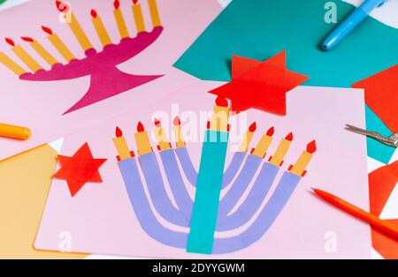 Una ragazza fa una carta per Hanukkah felice con le sue mani, un candelabro e candele sulla carta Foto Stock