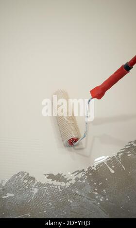 Operatore che applica un secchio di resina epossidica bianco sul pavimento Foto Stock