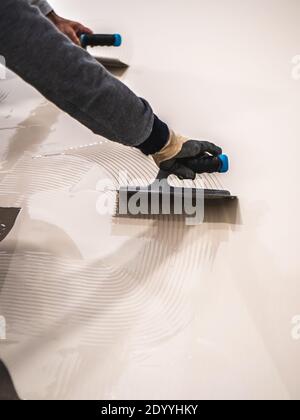 Operatore che applica un secchio di resina epossidica bianco sul pavimento Foto Stock