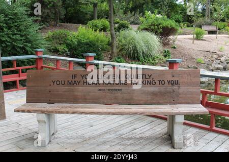 Una panchina del parco con una citazione di Don Hedberg incisa su di essa in un parco a Janesville, Wisconsin, in estate Foto Stock