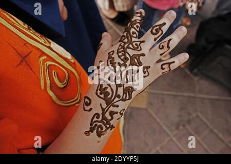 Donna in abito arancione con tatuaggio henné in Marocco, Marrakech, Africa del Nord. Foto Stock