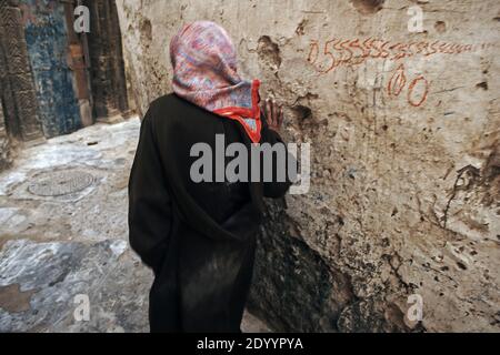 Donna è a piedi nella strada stretta e colorate vecchie case della medina medievale di Essaouira, Marocco Foto Stock