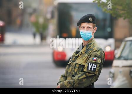 Un membro della polizia militare della repubblica ceca con una maschera facciale (telo chirurgico) in piedi su una strada cittadina. Foto Stock