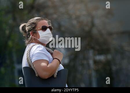 Donna con maschera in tessuto fatta a mano. A causa della mancanza di respiratori e maschere, gli abitanti di molti paesi li hanno cuciti da soli. Foto Stock