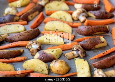 Ristorante, vegetarianismo, veloce, salute, ricette concetti - forno cotta verdure tagliate patate carote, funghi con aneto stagionante. Arrosto Foto Stock