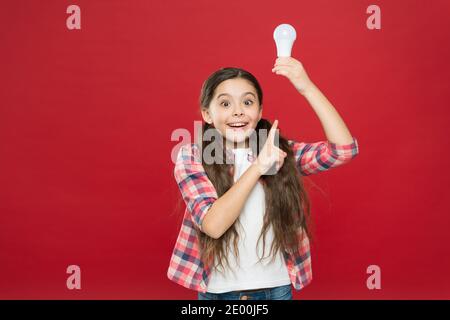 bambina stupita che punta il dito sulla lampadina con luce, ispirazione. Foto Stock