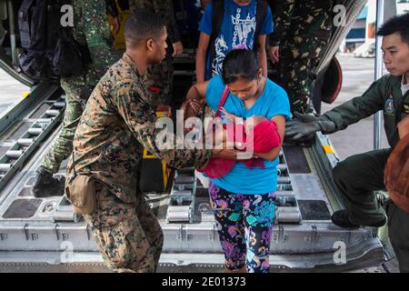 CPL. Lancia marina USA Xavier L. Cannon e i membri delle forze armate filippine aiutano i civili sfollati dal tifone Haiyan a sbarcare un aereo C-130 alla base aerea di Villamor, Filippine, 12 novembre 2013. I membri del servizio degli Stati Uniti stanno assistendo le forze armate delle Filippine mentre preparano gli sforzi di recupero per le persone colpite nel periodo successivo al tifone Haiyan. Foto di USMC via ABACAPRESS.COM Foto Stock