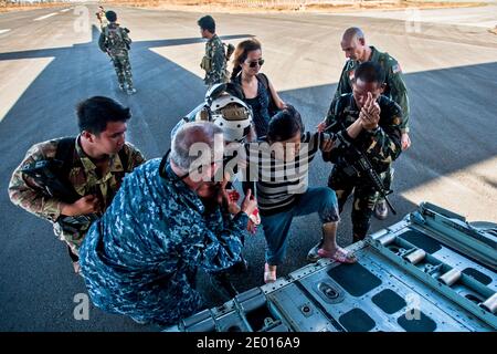 Marinai e soldati dell'esercito filippino aiutano una donna su un Hercules HC-130 da Marine Wing Support Squadron (MWSS) 172 per essere sollevato in aereo in una posizione più sicura. Il George Washington Carrier Strike Group sostiene la terza Brigata di spedizione marina per assistere il governo filippino nell'operazione Damayan in risposta alle conseguenze del Super tifone Haiyan/Yolanda nella Repubblica delle Filippine. Foto di US Navy via ABACAPRESS.COM Foto Stock