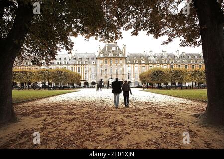 FRANCIA / IIe-de-France/Paris/ le Marais/ coppia che passeggiano mano nella mano in Place des Vosges, fiancheggiata da eleganti case a schiera. Foto Stock