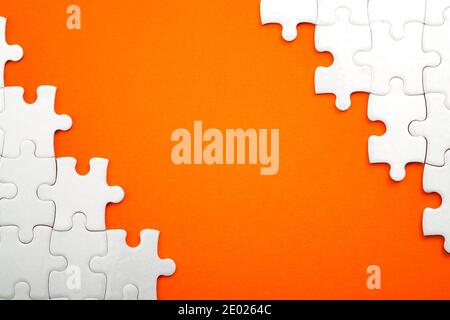 Puzzle pezzi e business concept con un bordo fatto di pezzi di puzzle su colorato sfondo arancione chiaro con copia spazio Foto Stock