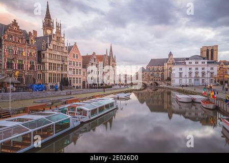 Gand, Belgio - Novembre 13 2014: La bella città vecchia storica di Gand, Belgio con barche per tour parcheggiate lungo il canale di Leie al tramonto Foto Stock