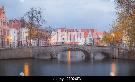 Un uomo si erge da solo sul Ponte di Carmers, nella splendida città vecchia di Bruges, in Belgio, al tramonto. Foto Stock