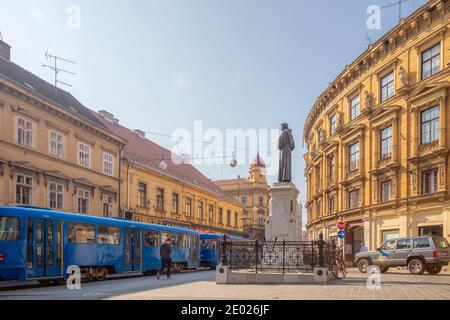 Zagabria, Croazia - 7 ottobre 2014: Un tram zips da una statua nel centro di Zagabria, la capitale della Croazia. Foto Stock