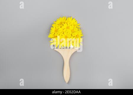 Pennello con fiori gialli su sfondo grigio. Colori dell'anno 2021: Grigio e illuminante. Concetto di colori alla moda, mockup con copia Foto Stock