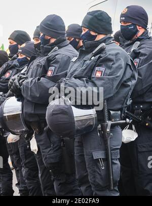 Braunschweig, Germania, 05 dicembre 2020: Poliziotti con cappelli neri e uniformi con baton tengono i loro caschi con visiere nel loro ha Foto Stock