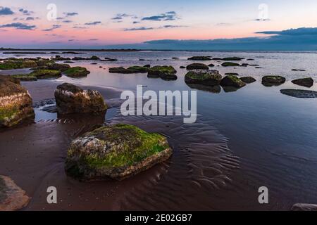 Alba colorata sulla costa rocciosa Foto Stock