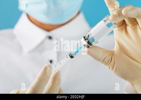 Fiala e siringa nelle mani di un medico ricercatore in guanti di gomma con un primo piano del vaccino e spazio libero per il testo sull'adesivo della fiala. Medico Foto Stock