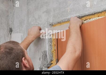 Un uomo incolla un nastro di carta bianca. Primo piano. Ristrutturazione della casa. Foto Stock