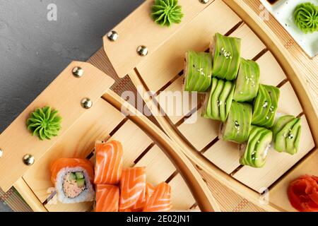 Rotolo e rotolo di sushi all'avocado con salmone servito su legno piastre Foto Stock