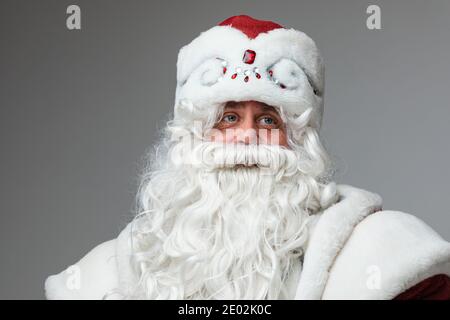Uomo maturo in cappello Santa con barba e baffi grigi, ritratto in studio, headshot su sfondo grigio Foto Stock