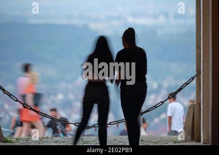 Due ragazze che sono occupate con i loro smartphone dentro Fronte di una catena e Open Urban Landscape e altro Persone in background Foto Stock