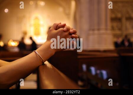 Closeup delle mani della donna che pregano sulla panchina della chiesa, coronavirus, spazio di copia Foto Stock
