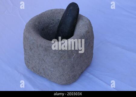 Pestello di pietra ruvido e mortaio isolato su sfondo blu Foto Stock