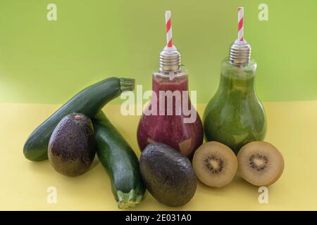 Frullati colorati con kiwi freschi, zucchine e avocado.Detox lampadine verdi e rosse bevande salutari . Concetto di supercibo su sfondo verde e giallo Foto Stock