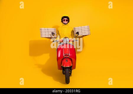 Ritratto fotografico della ragazza di consegna che tiene la scatola della pizza si impila dentro moto retrò rosso a due mani isolato su giallo vivo sfondo colorato Foto Stock