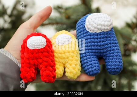 Crochet giocattolo membro equipaggio tra noi rosso giallo e blu Impostore Foto Stock