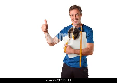 Uomo con bilancia e nastro di misurazione appeso vestito da sportswear e fondo bianco isolato. Foto Stock